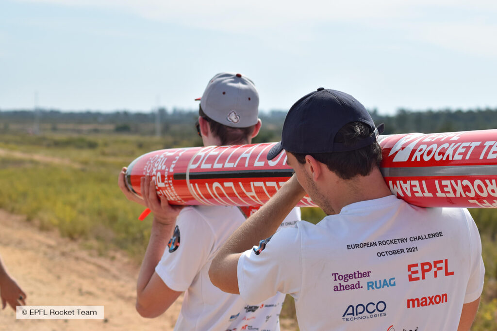 2 members of epfl rocket team carrying bella lui on their shoulders